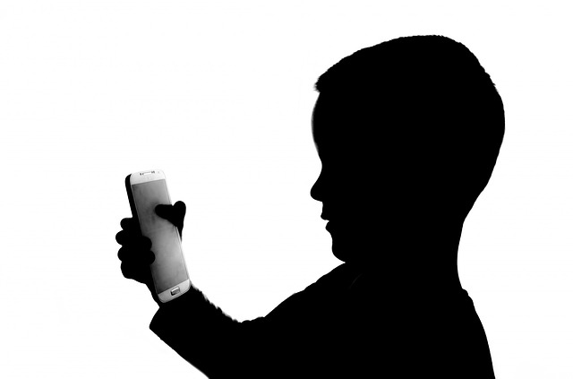 stín dítěte hledící na chytrý telefon na bílém pozadí